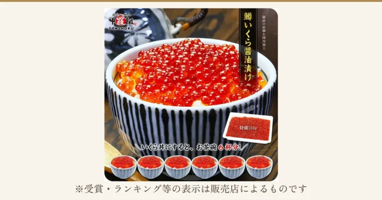 白いご飯にのせた鱒いくら醤油漬けの丼（染付の茶碗）と、トレーに入った越前かに職人甲羅組の商品、手前に小さな丼6杯を並べた商品写真。画像内に店舗ロゴ「越前かに職人 甲羅組 DENSHOKU」、縦書きの「鱒いくら醤油漬け」、店舗が画像に入れた表示「一級品の原卵を国内加工」「特盛500g」「いくら丼にすると、お茶碗6杯分！」あり。下に「※受賞・ランキング等の表示は販売店によるものです」
