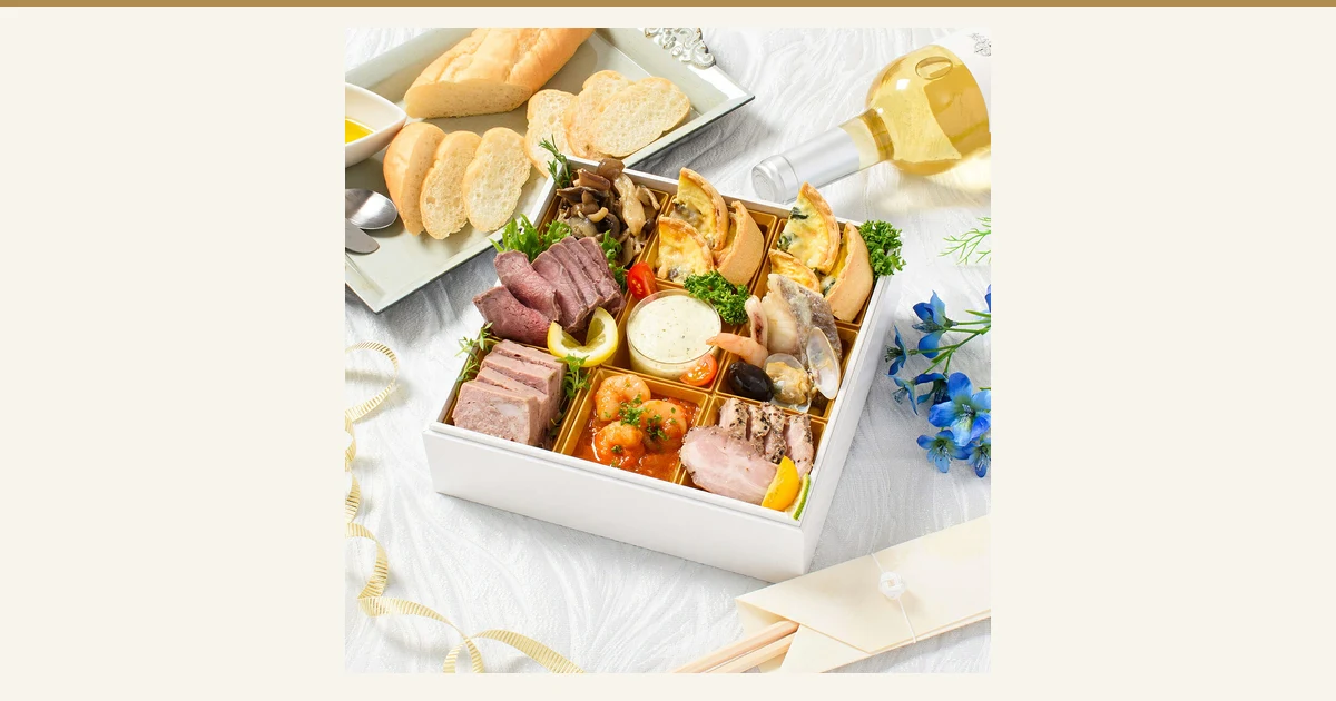 以彩色摆放在白色方形重箱中的洋风おせち『ヌイイ』料理套装照片为主、不加文字、居中放大制作的文章封面图。摆有烤牛肉、法式肉酱、法式咸派和虾类料理，并配有面包与白葡萄酒作为搭配