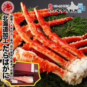 笹の葉の上に並べた赤いボイルたらばがにの脚。左下に脚が1本入った化粧箱の写真、縦書きで「北海道加工 たらばがに」の文字、右上にカニのキタウロコのロゴ