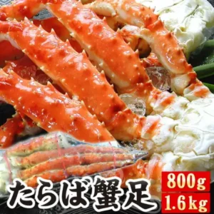 黒いトレーに砕いた氷と青ねぎを敷き、ゆで上げて赤く色づいたタラバガニの脚を殻付きのまま縦に並べた商品画像。手前左には真空パックに入った脚が重ねて置かれ、右側には白い身がのぞく関節部分が写っている。画像下部に「たらば蟹足」、右下に赤地白抜きで「800g」「1.6kg」の内容量表示。(厳選!北海道グルメ かに匠 タラバガニ脚)