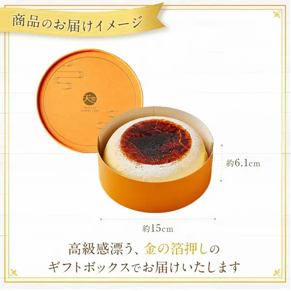 フォチェッタ 天空のチーズケーキ的礼盒照片。橙色圆形礼盒的盒盖被取下立在一旁，盒内放着1个舒芙蕾芝士蛋糕，盒盖上有金色的「天空」标志。图中标注的尺寸为高「約6.1cm」、宽「約15cm」，并有店铺放入图片中的标题「商品のお届けイメージ」和文字「高級感漂う、金の箔押しのギフトボックスでお届けいたします」。