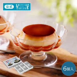 木の板の上に置いた、縁が花形の透明な脚付きの器に入ったカスタードプリン(上面と底にカラメル)の写真。左下に青と赤のストライプに帽子の絵が描かれた外箱と、「SHISEIDO PARLOUR」「CUSTARD PUDDING」と書かれた白い小箱6個。画像に店舗が入れた「公式」「SHISEIDO PARLOUR Est.1902 GINZA TOKYO」のロゴと「6個入」の表示。資生堂パーラー カスタードプリン 6個入