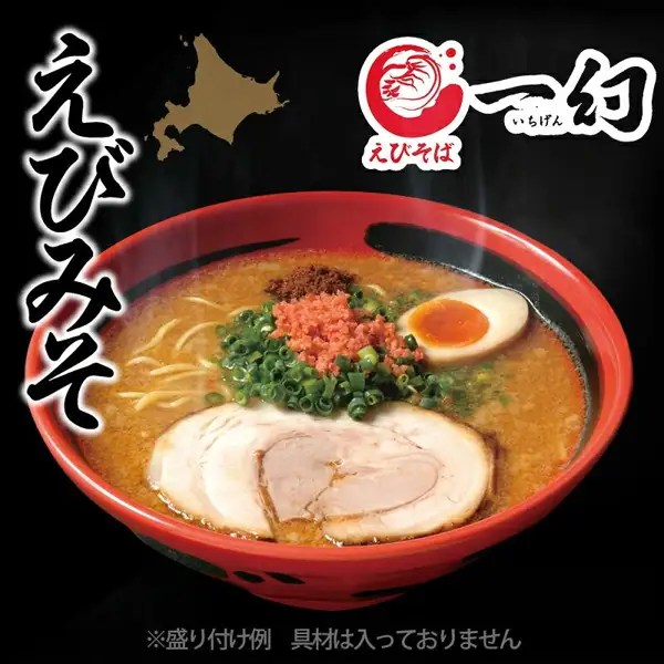 えびそば一幻 えびみその盛り付け例の写真。黒い背景に、赤い丼に入った味噌味のラーメンが写り、チャーシュー・味付け卵・ねぎ・赤い粉状のトッピング・茶色の粉状のものがのっている。左に縦書きの「えびみそ」、北海道の地図の形、右上に「えびそば 一幻（いちげん）」のロゴ。店舗が画像に入れた表示：「えびみそ」「※盛り付け例 具材は入っておりません」