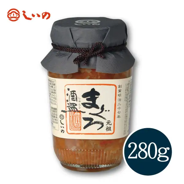 Single product photo of a 280g jar of Shiino Shokuhin's Maguro Shutou on a white background. A jar with a black cloth cap tied with cord. The front label reads 「まぐろ　酒盗」(Maguro Shutou). The jar has 「元祖」and 「創業明治二十七年」written on it. The shop's logo is at the top left of the jar and a dark circle at the bottom right reads 280g. The contents are a thick, reddish-brown fermented tuna innards mixture.