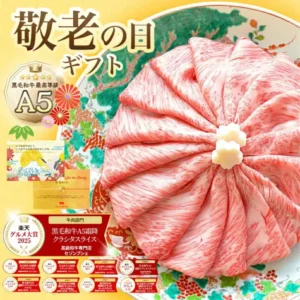 森田商店(セゾンブシェ)の黒毛和牛A5等級 霜降りクラシタロース スライス500gを、松と花柄の和皿にロゼット状に盛り付け、中央に花形の白い飾り2個を添えた商品画像。左側にメッセージカードとのし紙の見本(「いつもありがとう いつまでも元気で長生きしてね」「祝 敬老の日」の文字)を重ねている。画像内には「敬老の日ギフト」の見出し、「黒毛和牛最高等級A5」のバッジ、「楽天グルメ大賞2025」と2016〜2020年・2022〜2024年分(計9個)の受賞バッジ、「牛肉部門 黒毛和牛A5霜降クラシタスライス 高級和牛専門店セゾンブシェ」の表示があります。