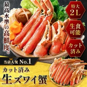 黒い石の台に置いた土鍋風の器に、カット済みの生ずわいがにの棒肉と爪を立てかけて盛り、背後に白菜・しいたけ・えのき・輪切りにんじんを添えた鍋用の盛り付け写真。右下には黒い皿に脚をびっしり並べた別カットが入る。左に「最高水準の高鮮度。」、右に「特大2L」「生食可能」「カット済み」、下に「カット済み 生ズワイ蟹」の文字。(港ダイニングしおそう ズワイガニ カット済み600g)