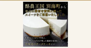 Product photo of a round white cheesecake with one cut slice taken out, set side by side on a dark stone-like stand (Rich Cheesecake BETSUKAI, a furusato nozei thank-you gift from Betsukai Town, Hokkaido). Text the shop placed in the image reads “酪農王国 別海町から 地元の素材を贅沢に使ったスイーツをご用意いたしました” (From Betsukai, the dairy kingdom: sweets made lavishly with local ingredients) and “新鮮なべつかい牛乳と、大自然でのびのび育った鶏卵を原料とした北海道のチーズケーキです” (A Hokkaido cheesecake made from fresh Betsukai milk and eggs from hens raised freely in nature)