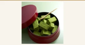 蓋を外した赤い丸い器に盛った、抹茶の粉をまとった角形の生チョコの写真（盛り付け例）。宇治抹茶 生チョコ 16粒 抹茶味（伊藤久右衛門）