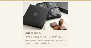 ショーコラ＆パリトロ 4個入（バニラビーンズ）の記事アイキャッチ。商品写真。ふたを外した黒いギフト箱に黒い個箱が並び、見えている3つのうち1つに「CHOCOLAT」「Bitter chocolate」、2つに「PARIS TROIS」「Sweet」「VANILLABEANS」の文字。手前に「VANILLABEANS chocolatier」のロゴ入りの黒いふた、右手前の白い皿にチョコレートでコーティングされた四角いパリトロ2個と、クッキーでチョコレートをはさんだショーコラ（立てた1個と、切って断面を見せた1切れ）。店舗が画像に入れた表示「高級感のあるクラシックなパッケージデザイン。」「身近な方へのギフトはもちろん、お歳暮やお中元、ビジネスシーンなどのフォーマルなギフトにも最適です。」