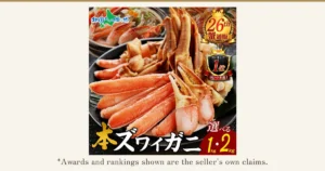 A black plate holding half-cut snow crab leg meat and claws, with the shell halved; a pot with crab in it sits behind. Product photo of the Kitaguni kara no Okurimono Snow Crab Kani-Shabu Set. Text the shop placed in the image reads: the "北国からの贈り物" logo, "26th" with "蟹通販" (crab mail order), "ランキング1位 リピート多数!" (Ranking No. 1, many repeat buyers), "本ズワイガニ" (true snow crab) and "選べる 1kg・2kg" (choose 1kg or 2kg). Below the photo: "*Awards and rankings shown are the seller's own claims."