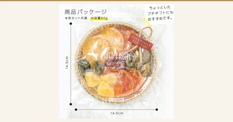 透明な袋に入った丸い編みかご風のトレイに、輪切りのドライフルーツや黄色い角切りなどが円形に盛られた、国産ドライフルーツ 食べ比べ7種（定番セット）山下屋荘介の商品パッケージ写真。トレイに麻ひもと赤い札が付き、袋の左右と下に寸法線がある。店舗が画像に入れた表示「商品パッケージ」「※各セット共通 内容量80g」「ちょっとしたプチギフトにもおすすめです。」、寸法「14.5cm」「14.5cm」。袋の印字「NATURAL FOODS」「DRIED FRUITS」「ドライフルーツ」「Yamashitaya KITCHEN」、札「ESPECIALLY FOR YOU」。