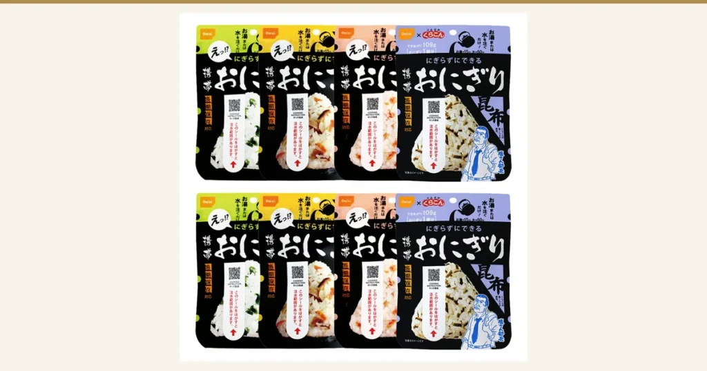 尾西食品 携帯おにぎり8食分（五目・昆布・鮭・わかめ各2個）の商品写真。黒地の袋が上下2段に4袋ずつ、計8袋並んでいる。左から わかめ・五目・鮭・昆布の袋で、袋に印刷された表示「携帯おにぎり」「にぎらずにできる」「長期保存対応」「写真はイメージです」