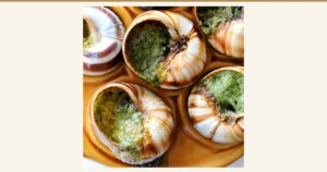 Baked shell-on escargot arranged in the hollows of a plate. Green butter fills the spiral, striped shells. Introduction image for ハイ食材室's “Escargot à la Bourguignonne from France, Shell-On with Butter, 30 Pieces”. No text is baked into the image.
