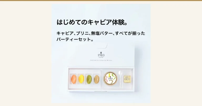 Product photo of the Miyazaki Caviar 1983 (12g) & Blini Set: inside a white gift box lie four blini in orange, yellow, green and brown, a caviar jar with a white, gold-rimmed lid printed with “1983”, a shell spoon and a gold-wrapped butter. Text the shop placed in the image reads “はじめてのキャビア体験。” (Your first caviar experience.) and “キャビア、ブリニ、無塩バター、すべてが揃ったパーティーセット。” (A party set with caviar, blini and unsalted butter, all included). The box and lid are printed with “1983 J.CAVIAR” and “CAVIAR & Colorful Blinis”.