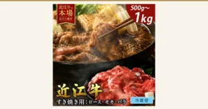 Product photo of Omi Gyu loin, momo (round), and bara (short plate) for sukiyaki: chopsticks lifting a piece of beef out of a sukiyaki pot that also holds grilled tofu, napa cabbage, shiitake mushrooms, green onions, and garland chrysanthemum, with raw thin-sliced beef on a plate in front. Text the shop placed in the image: “近江牛の本場” (home of Omi Gyu), “近江八幡市” (Omihachiman City), “500g〜1kg”, “近江牛” (Omi Gyu), “すき焼き用：ロース・モモ・バラ” (for sukiyaki: loin, momo, bara), “冷蔵便” (chilled delivery)