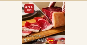 生ハム専用豚肉 アンダルシアポーク ミニ原木的封面图。木砧板上，刀正切向一块生火腿，前方摆着切成薄片的生火腿的商品照片。店铺在图片中加入的标示「ギフト対応」「アンダルシアポーク 生ハムミニ原木」「スペイン産」。