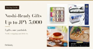 Featured image with a black label “Buying Guide” on a cream ground at the left, the headline “Noshi-Ready Gifts”, “Up to JPY 5,000”, “5 gifts, one yardstick” and “Noshi, wrapping and delivery”, and four product photos in a 2 by 2 grid at the right: Tsukuda no Tsukudani (佃の佃煮) taste-test set (a white gift box with three ochazuke packs and a tray of six tsukudani), Kishu Takashita Suisan (紀州高下水産) Kishu Nanko-ume dashi ochazuke (a gift box with a fish-print design and the small pouches inside the opened box), Shiseido Parlour (資生堂パーラー) custard pudding (a footed glass dish and its outer box) and Enjin (煙神) smoked cheese set (five kinds of smoked cheese on a wooden board; the crackers, salad leaves and raisins are a serving example and are not included with the product). The photos carry text the shops put in the images, including “大切な人へ感謝の気持ちを専用の化粧箱でお届けします”, “和食”, “公式”, “6個入”, “商品内容”, “5種の燻製チーズセット” and “発送方法：冷蔵便”