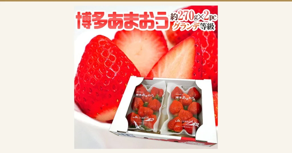 Product photo of a box holding two packs of Amaou strawberries, with cut strawberries in the background. Text the store added to the image: “博多あまおう” (Hakata Amaou), “約270g×2pc” (about 270 g × 2 packs), “グランデ等級” (Grande grade)