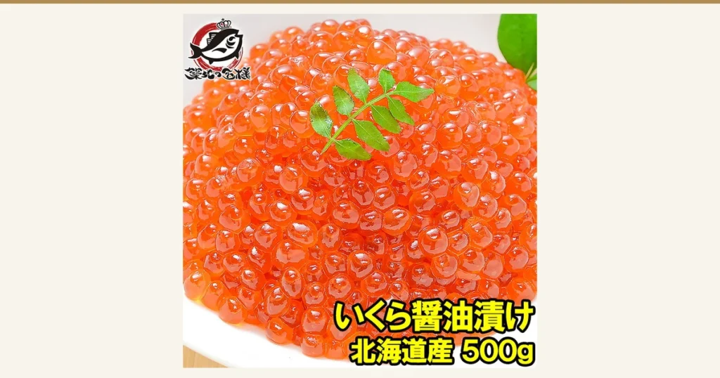 Product photo of soy-marinated salmon roe (ikura) heaped on a white plate with a leaf garnish (soy-marinated ikura 500g, Hokkaido salmon roe, from 築地の王様). The store logo “築地の王様” is at the top left. Text the store added to the image: “いくら醤油漬け” (soy-marinated ikura) and “北海道産 500g” (Hokkaido, 500g)