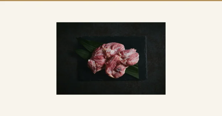 Product photo of Purebred Nagoya Cochin Chicken Thigh 1kg, Morning-Slaughtered: raw chicken thighs arranged on black slate lined with bamboo leaves. No text appears in the image.