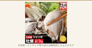 ジャンボ広島カキ 2kg（加熱用）のアイキャッチ。土鍋の鍋料理の中で、大粒のかきのむき身を箸でつまんだ寄りの写真（奥の白菜・長ねぎ・にんじんは商品に含まれません）。右上に店舗ロゴ「越前・若狭のさかな屋さん ますよね」、店舗が画像に入れた表示として左下に「広島産」「ジャンボ」「牡蠣」「メガ盛り」「2kg」の文字、右下に金色のバッジで「SHOP OF THE YEAR」「海産物ジャンル賞」「楽天 2017」の文字。写真の下に「※受賞・ランキング等の表示は販売店によるものです」