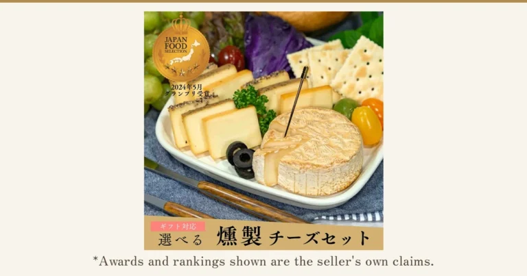 Product photo of smoked cheese on a plate (the 煙神 Enjin choose-your-own smoked cheese assortment), showing rectangular cheeses topped with black pepper, smoked cheese and a cut round camembert-type cheese. Crackers, grapes, olives, cherry tomatoes, parsley and red cabbage are also on the plate as a serving example and are not included with the product. Text the store added to the image: “JAPAN FOOD SELECTION”, “2024年5月 グランプリ受賞”, “ギフト対応”, “選べる 燻製チーズセット”. Below it: “*Awards and rankings shown are the seller's own claims.”