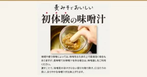 上方以大字写着「麦みそでおいしい」「初体験の味噌汁」，中间的照片里，一只手用木杵把金属味噌滤网里的大麦味噌压过滤网，溶进下方的锅中。照片下方写着「地域や使う味噌によっては、味噌をおたまの上で直接溶く場合もありますが、麦味噌でお味噌汁を作る場合は、味噌漉しをご利用ください。」「漉すことで、味噌麦の溶けきらない部分を取り除き、口当たりの良い、まろやかな味噌汁が出来上がります。」（店舗在图片中加入的标示）。 麦みそや 麦味噌（大麦味噌）甘口 500g×5（味噌の通販 麦みそや）