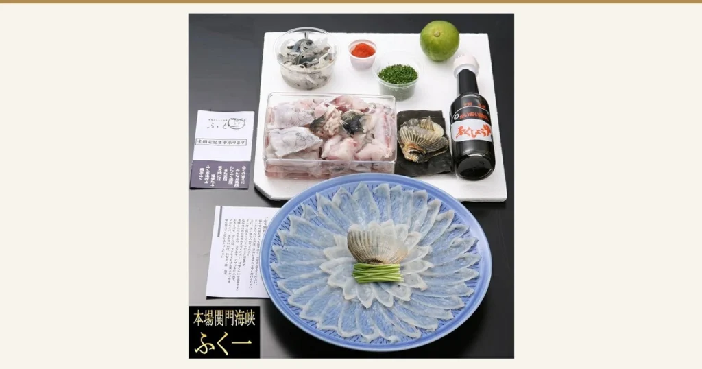 Photo of torafugu sashimi arranged radially on a blue plate, with a white board above it holding a container of fugu chiri pieces, a small container of cut pieces, fins on kelp, grated daikon with chili, chopped chives, a kabosu citrus and a bottled sauce, and two leaflets at the left (ふく一 Torafugu Sashimi and Fugu Hot Pot Set, 2–3 Servings). Text the shop put in the image: “本場関門海峡 ふく一” and “全国宅配年中承ります”