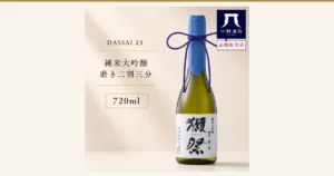 獺祭 純米大吟醸 磨き二割三分 720mlの商品写真。青い和紙で首元を包み紫色の紐を結んだ緑色のボトルが右に立ち、白いラベルに「獺祭」「DASSAI 23」「純米大吟醸 磨き二割三分」の文字がある。店舗が画像に入れた表示として、左に「DASSAI 23」「純米大吟醸 磨き二割三分」「720ml」、右上に「小野酒店」のロゴと「正規販売店」の文字あり