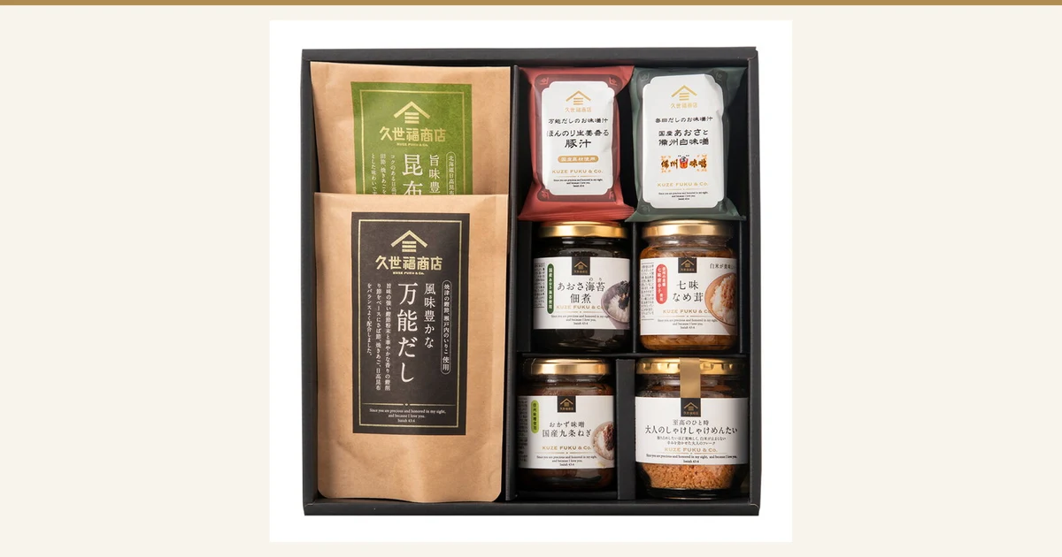 Featured image. Product photo of the Kuzefuku Shoten Gohan no Otomo Gift (with gift box, 8-item set). Inside a black gift box are two paper pouches of kombu dashi and all-purpose dashi, two miso soup packets (pork miso soup and aosa seaweed miso soup), and four jars (aosa nori tsukudani, shichimi nameko, okazu miso, and shake-shake mentaiko flakes), eight items in total. Text printed on the product packaging includes "久世福商店" and "国産具材使用".