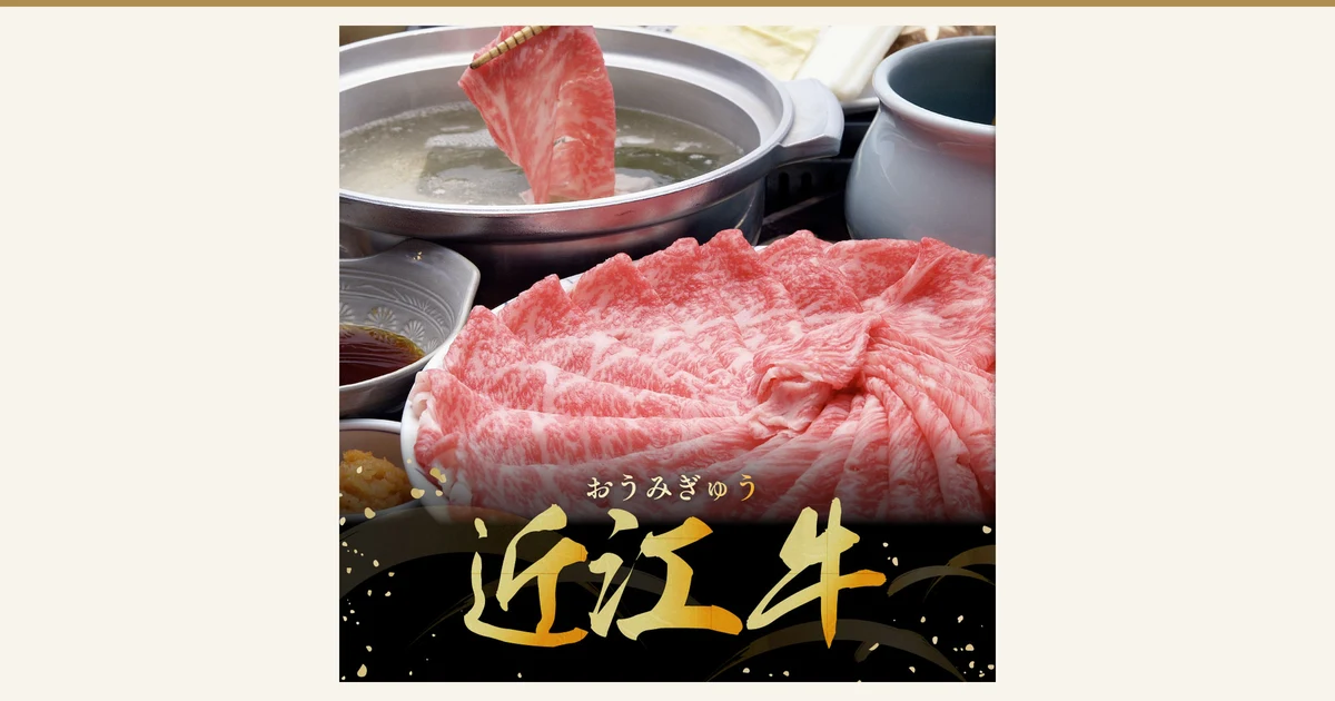 湯を張った鍋に箸で薄切りの牛肉をくぐらせる様子と、皿に広げた霜降りの牛肉スライス、左に茶色のたれと薬味の小鉢、鍋の奥に豆腐やねぎとみられる具材が写る商品写真(千成亭 近江牛 肩ロース しゃぶしゃぶ 500g)。店舗が画像に入れた表示として「おうみぎゅう」「近江牛」の文字
