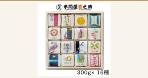 米問屋蔵之助 お米ギフト 食べ比べ 2合16種 木箱入りの商品写真。木箱の中に、銘柄ごとに絵柄の違う白い小袋が4列×4段で16袋並んでいる。店舗が画像に入れた表示として、上部に店舗ロゴ「米問屋蔵之助 KOMEDONYA KURANOSUKE」、下部に「300g× 16種」の文字あり。