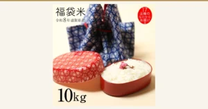 木村商店 滋賀県産 福袋米 10kg の記事アイキャッチ。赤い漆器の飯碗によそった白米（桜の花びら付き）と、藍色の風呂敷包みの商品写真。画像内に店舗が画像に入れた表示「福袋米」「令和8年 滋賀県産」「10kg」「17品種のなかからお届け」がある。