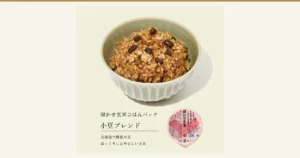 Photo of azuki bean blend nekase genmai (aged brown rice) served in a pale green bowl, with a round pink pack container at the lower right (one of the varieties in the 結わえる Nekase Genmai 4-Variety Mix, 6-Meal Trial Set). Text the store added to the image: “寝かせ玄米ごはんパック” (nekase genmai rice pack), “小豆ブレンド” (azuki blend), “北海道十勝産小豆” (azuki from Tokachi, Hokkaido), “ほっくりしたやさしい甘み” (a soft, gentle sweetness). Text on the pack label: “特許製法”, “圧力釜で炊いたもちもち食感”, “寝かせ玄米”, “小豆”