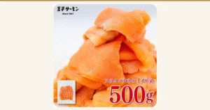 白い背景に、大きなスライスのスモークサーモンを山のように重ねた商品写真（王子サーモン 業務用スモークサーモン 切り落とし 500g）。左下に袋に入ったスモークサーモンの小さな写真。店舗が画像に入れた表示として「王子サーモン」「Since 1967」「スライス大きめ！大容量」「500g」の文字