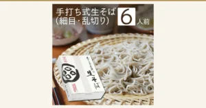Product photo of fine teuchi-style fresh soba piled on a bamboo zaru, with a white box marked with the Naraya fresh soba (生そば) name in front (Okuaizu Naraya Teuchi-Style Fresh Soba, 6 Servings with Tsuyu). Text the shop placed in the image: “手打ち式生そば（細目・乱切り）” and “6人前”