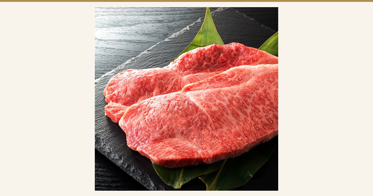 仙台牛 サーロインステーキ（西冷牛排）200〜220g×2片的商品照片：黑色石板上铺着绿色竹叶，上面重叠摆放着2块带有细密雪花纹的红色牛西冷牛排肉。