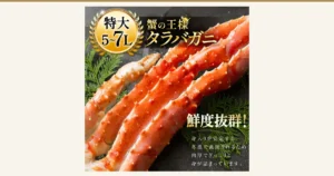 黒い背景に置かれた、ボイル済みのタラバガニの脚の商品写真(本タラバガニ脚 ボイル済)。画像内に店舗が画像に入れた表示として、「特大 5~7L」「蟹の王様 タラバガニ」「鮮度抜群!」と「身入りが安定する冬漁で漁獲されるため肉厚でぎっしりと身が詰まっています。」の文字あり。