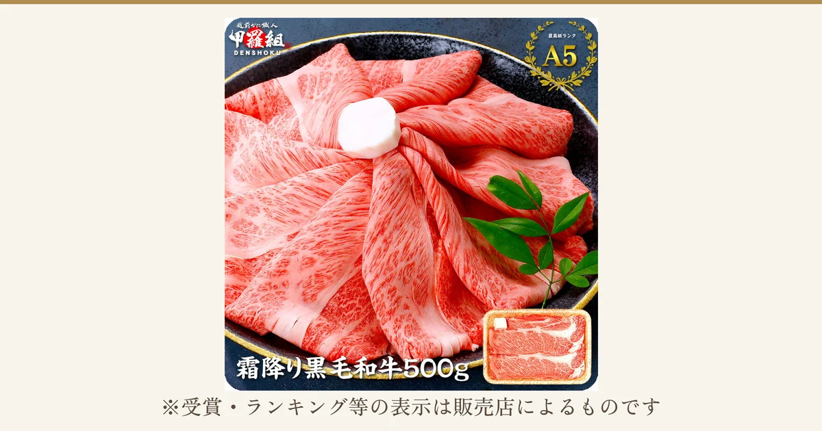 黒い器に薄切りの黒毛和牛を広げて盛り、緑の葉を添えた甲羅組 国産黒毛和牛スライス500gの商品写真。右下にトレイに入ったスライス肉の小さな写真。画像内には店舗が画像に入れた表示として、店舗ロゴ「越前かに職人 甲羅組 DENSHOKU」、月桂冠つきの「最高級ランク A5」、「霜降り黒毛和牛500g」の文字がある。写真の下に「※受賞・ランキング等の表示は販売店によるものです」