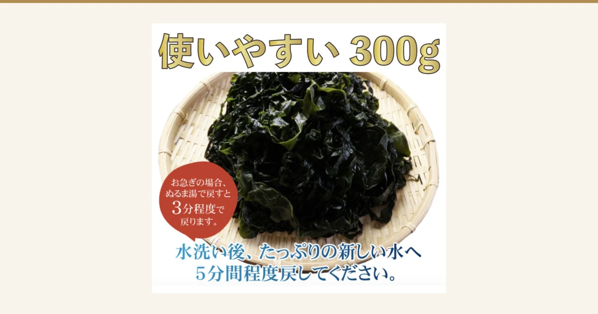 Product photo of dark green wakame heaped on a bamboo sieve. The top reads “使いやすい 300g”, a reddish-brown circle at the lower left reads “お急ぎの場合、ぬるま湯で戻すと3分程度で戻ります。”, and the bottom reads “水洗い後、たっぷりの新しい水へ5分間程度戻してください。” (text the shop placed in the image). 黒潮海苔店 Blanched and Salted Wakame 300g, Sanriku-labeled (produced in Noda Village, Iwate Prefecture)
