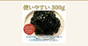 竹筛上堆满深绿色裙带菜的商品照片。上方写着「使いやすい 300g」，左下的红褐色圆圈里写着「お急ぎの場合、ぬるま湯で戻すと3分程度で戻ります。」，下方写着「水洗い後、たっぷりの新しい水へ5分間程度戻してください。」（店铺加入图片的标示）。黒潮海苔店 三陸産（岩手県野田村産）湯通し塩蔵わかめ（烫煮盐渍裙带菜）300g