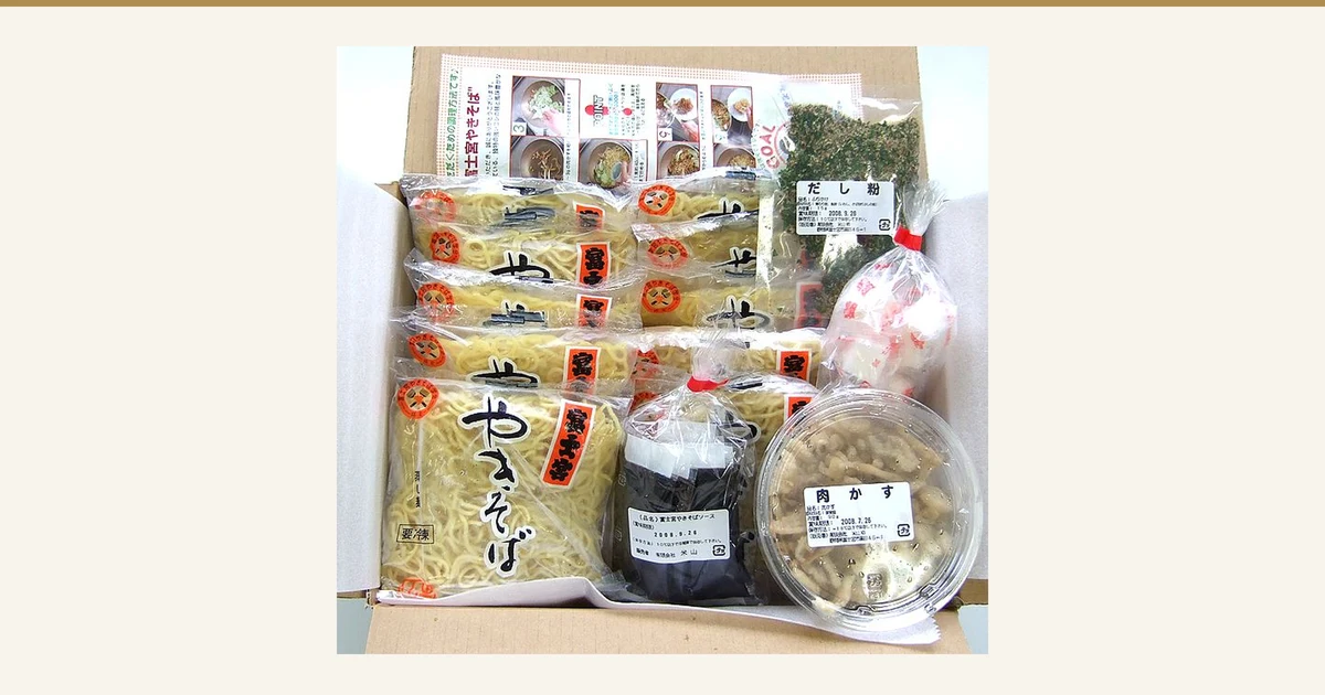 Featured image for the Tokusen Fujinomiya Yakisoba 10-Serving Set (Yoneyama). A product photo of a cardboard box packed with bags of steamed yakisoba noodles, a bag of dashi powder, a tub of nikukasu and a bag of sauce. The package labels read “だし粉” (dashi powder), “肉かす” (nikukasu) and “富士宮やきそばソース” (Fujinomiya yakisoba sauce).