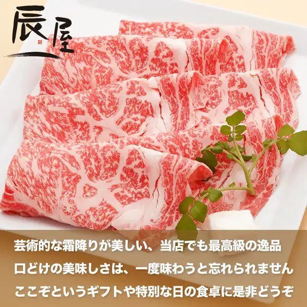 Product photo of thin slices of Kobe Gyu sukiyaki meat (Tokusen Loin) spread on a white square plate with watercress. The shop logo "辰屋" is at the upper left and three lines of text sit on a brown band at the bottom (Kobe Gyu Specialty Shop Tatsuya, Kobe Gyu Sukiyaki Meat, Tokusen Loin). Text the shop placed in the image: "芸術的な霜降りが美しい、当店でも最高級の逸品" (the shop's wording: beautiful artistic marbling, a top-grade item even among its own range), "口どけの美味しさは、一度味わうと忘れられません" (the shop's wording: a melt-in-the-mouth taste you won't forget once tried), "ここぞというギフトや特別な日の食卓に是非どうぞ" (the shop's wording: recommended for important gifts and special-day tables)