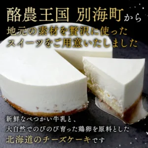 Product photo of a round white cheesecake with one cut slice taken out, set side by side on a dark stone-like stand (Rich Cheesecake BETSUKAI, a furusato nozei thank-you gift from Betsukai Town, Hokkaido). Text the shop placed in the image reads “酪農王国 別海町から 地元の素材を贅沢に使ったスイーツをご用意いたしました” (From Betsukai, the dairy kingdom: sweets made lavishly with local ingredients) and “新鮮なべつかい牛乳と、大自然でのびのび育った鶏卵を原料とした北海道のチーズケーキです” (A Hokkaido cheesecake made from fresh Betsukai milk and eggs from hens raised freely in nature)