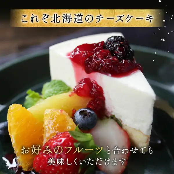 ベリーのソースと黒いベリーをのせたチーズケーキ1切れに、オレンジ、いちご、ブルーベリー、黄色い果物、ミントを添えて深緑の皿に盛った、濃厚チーズケーキ BETSUKAI〜べつかい〜（北海道別海町のふるさと納税）の商品写真。店舗が画像に入れた表示：「これぞ北海道のチーズケーキ」「お好みのフルーツと合わせても美味しくいただけます」