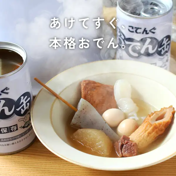 天狗缶詰 おでん缶 こてんぐ 長期保存 牛すじ大根入り（长期保存关东煮罐头，含牛筋・萝卜）盛入器皿的照片。白色器皿中盛有串在竹签上的三角蒟蒻、萨摩炸鱼饼、打结的丝蒟蒻、鹌鹑蛋2个、萝卜、牛筋肉和竹轮，并冒着热气。左侧是已打开、可见汤汁的罐头，后方是写有“こてんぐ”“おでん缶”的罐头。图片内店铺放入的标示为“あけてすぐ、本格おでん。”。此为盛入器皿的示例，器皿不包含在商品内。