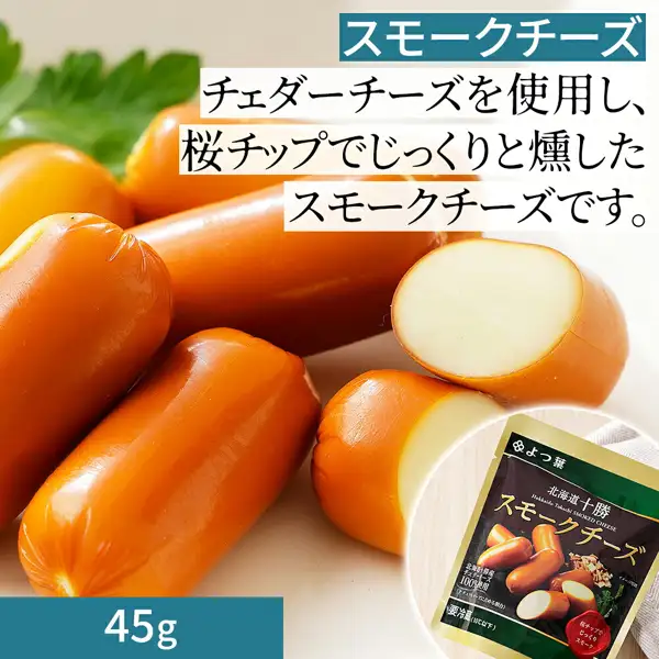 オレンジ色の表面のスティック状のスモークチーズ7本ほどを並べた写真。うち2本は切り口の白っぽい断面が見える。右下に袋入りの「北海道十勝 スモークチーズ」のパッケージ、左奥にパセリの葉。店舗が画像に入れた表示「スモークチーズ」「チェダーチーズを使用し、桜チップでじっくりと燻したスモークチーズです。」「45g」。よつ葉 バター・チーズ詰め合わせ【A】バター・チーズAセットに入る北海道十勝 スモークチーズ