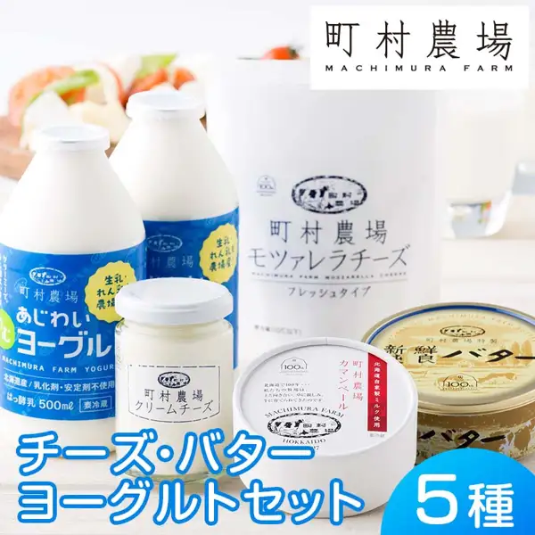 町村農場 チーズ・バター・ヨーグルトセットの商品写真。のむヨーグルトの瓶2本・クリームチーズの瓶・モツァレラチーズの袋・カマンベールチーズの丸箱・新鮮純良バターの缶を並べ、背景にトマトと緑の葉を添えた白いチーズの皿とグラスが写っている。店舗が画像に入れた表示「町村農場 MACHIMURA FARM」「チーズ・バター ヨーグルトセット」「5種」