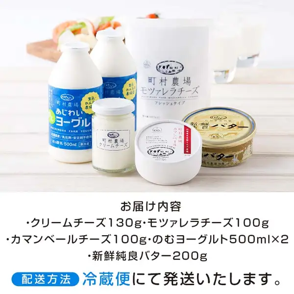 Photo of the contents of Machimura Farm Cheese, Butter and Yogurt Set: two 500 ml bottles of drinking yogurt, a jar of cream cheese, a pouch of mozzarella, a round box of Camembert and a tin of 新鮮純良バター (butter), with a board of white cheese garnished with tomato and green leaves and two glasses in the background. Text added to the image by the store (contents list and chilled delivery notice): 「お届け内容」「・クリームチーズ130g・モツァレラチーズ100g」「・カマンベールチーズ100g・のむヨーグルト500ml×2」「・新鮮純良バター200g」「配送方法 冷蔵便にて発送いたします。」