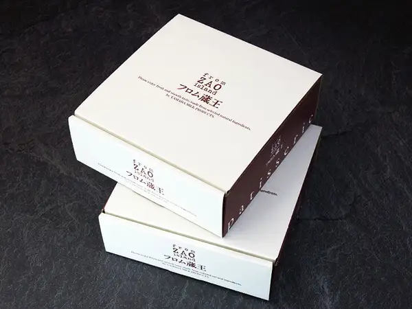 Photo of two small white boxes with the フロム蔵王 logo, stacked on a black slate-style surface (フロム蔵王 大感動！濃厚チーズケーキ2個セット)